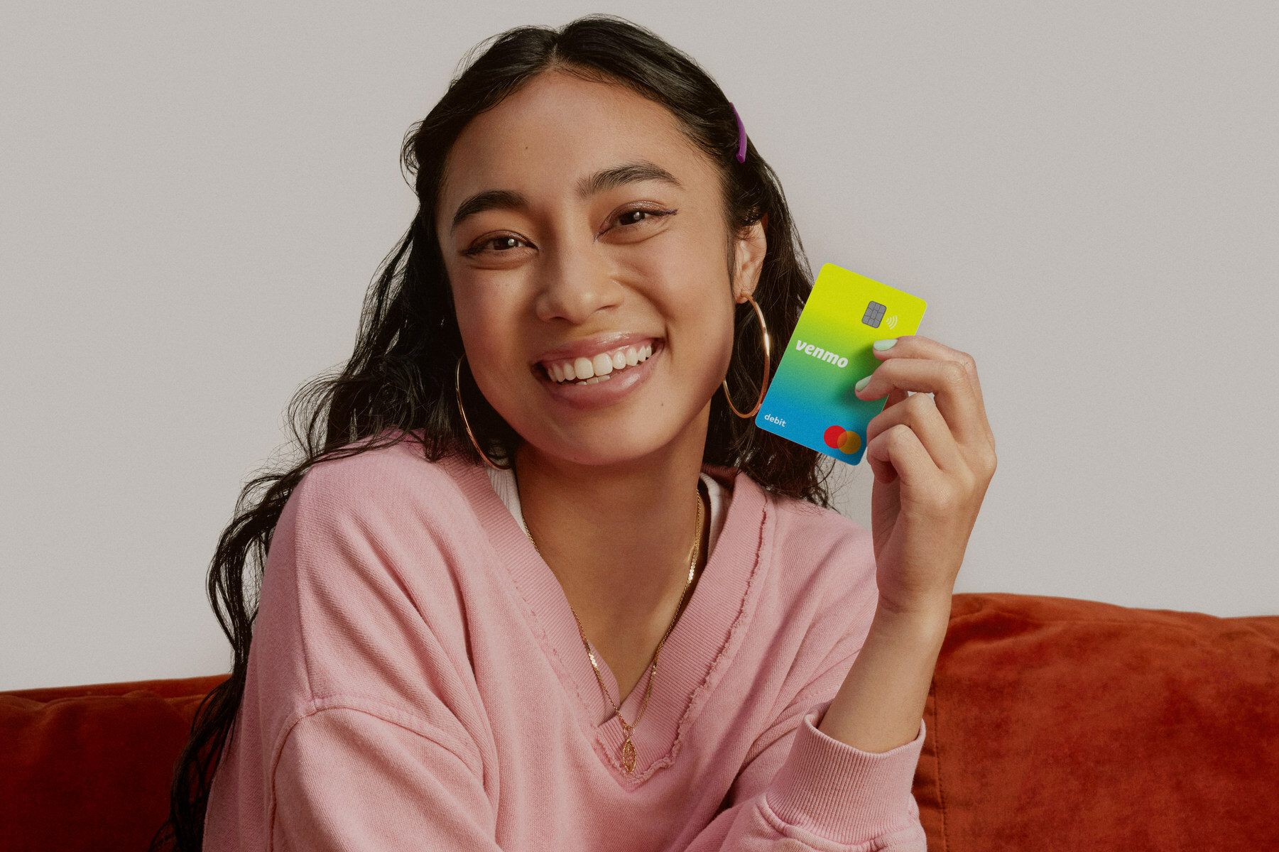 A young teen sits on a couch holding a Venmo card.